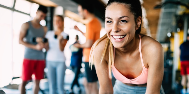Wenn Trainings-Fehler teuer werden Eine Frau im Fitnessstudio lacht nach ihrem Workout.